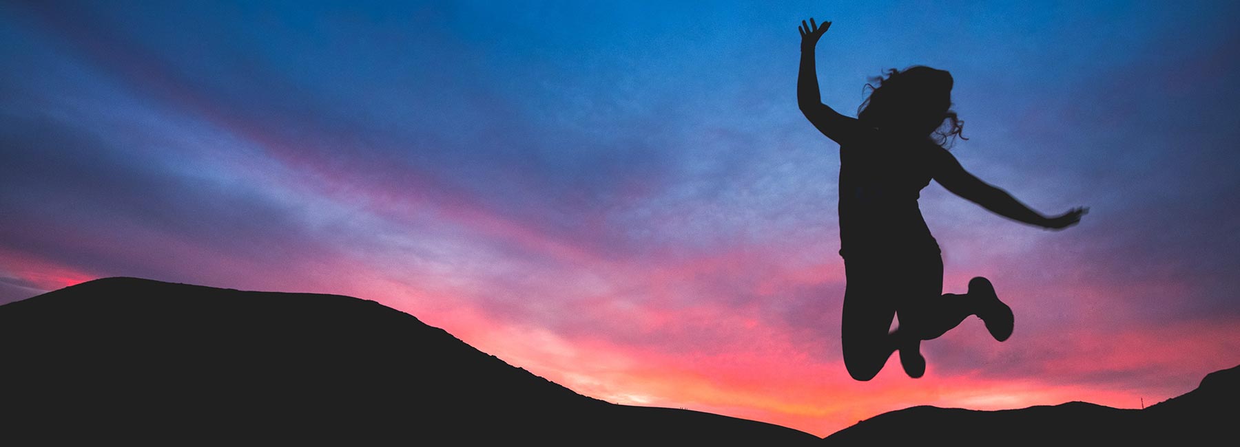 A teenager jumping with a sunset in the background illustrating an article on wilderness therapy for teen adhd treatment | RedCliff Ascent